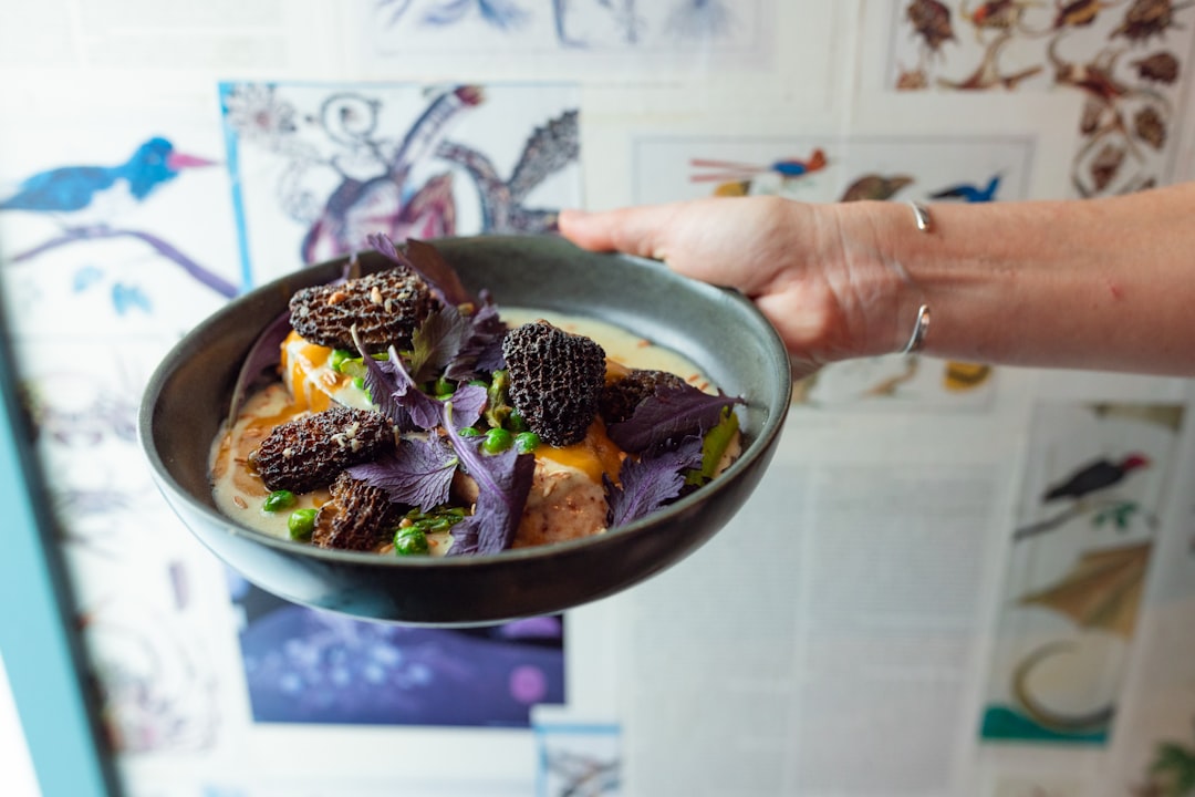 Hands holding a small bowl of food.